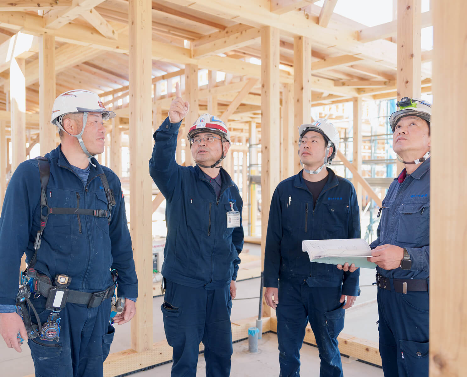 住宅の建築現場で図面を確認しながら施工の打ち合わせを行うヒタチ設備の技術者